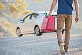 Man carrying gas can to car at roadside