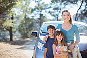Portrait of happy family leaning on car