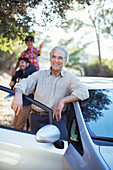 Senior man leaning against car