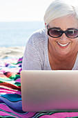 Happy woman using laptop on beach
