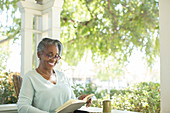 Happy senior woman reading book on porch