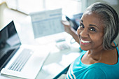 Smiling woman paying bills at laptop