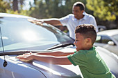 Grandfather and grandson wiping car