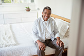 Smiling senior man sitting on bed