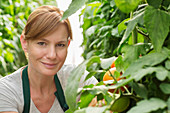 Woman next to tomato plants in greenhouse