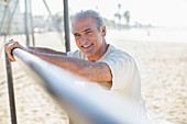 Senior man leaning on bar at beach