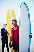 Portrait of senior couple with surfboards