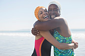 Women hugging in bathing suits and caps