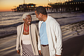 Senior couple walking on beach at sunset