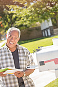 Smiling man retrieving mail from mailbox