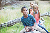 Children sitting on log in forest