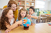 Students and teacher examining globe