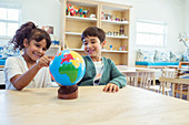Students examining globe in classroom
