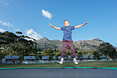 Boy jumping on trampoline outdoors