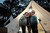 Children hugging by teepee at campsite
