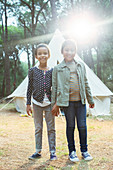 Girls smiling by teepee at campsite