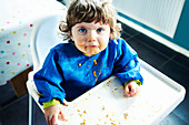 Messy baby girl eating in high chair