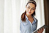 Woman using digital tablet by window