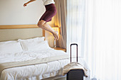 Businesswoman jumping on bed