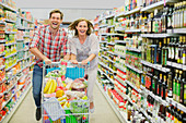 Couple playing with shopping cart aisle