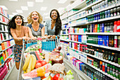 Women playing with shopping cart aisle