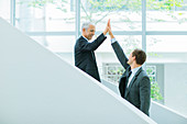 Businessmen high fiving on staircase