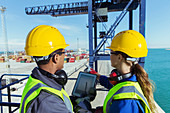Workers using tablet on cargo crane