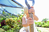 Girl holding shovel in sunny garden