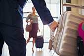 Man wearing suit grabbing silver suitcase