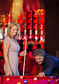 Woman and man playing pool in bar