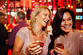 Two smiling mature women enjoying drinks