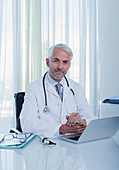 Mature doctor at desk with laptop