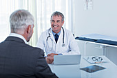 Smiling mature doctor and man at desk