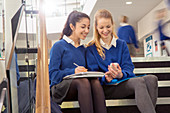 Two female students sitting on steps