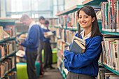 Student holding books in library
