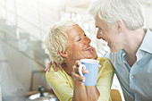 Older couple hugging with coffee cup