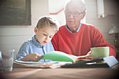 Boy reading with grandfather at table
