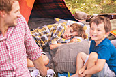 Father and sons smiling at camping tent