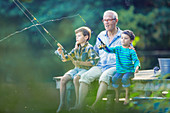 Grandfather and grandsons fishing in lake