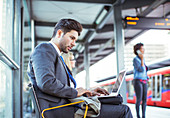 Businessman using laptop at train station