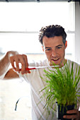 Man cutting potted plant with scissors