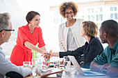 Office workers shaking hands at desk