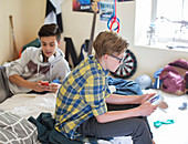 Boys using digital devices in room