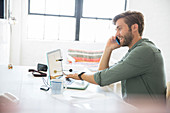 Man sitting with mobile phone and laptop