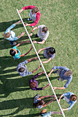 Team holding pole up with fingertips