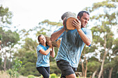 Man and woman running with logs