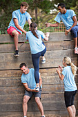 Teammates helping woman over wall