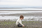 Girl picking up pebbles on beach