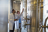 Vintners in lab coats checking vats
