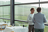 Men talking at winery dining room window